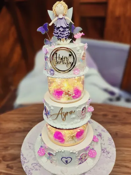 A grand five-tier fairy cake that is pure magic. With alternating tiers filled with lights and flowers, and topped with a beautiful fairy, this cake was a breathtaking centerpiece for a special celebration.