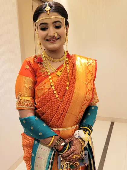 An orange silk saree draped in the traditional Maharashtrian style for this bride's wedding ceremony.