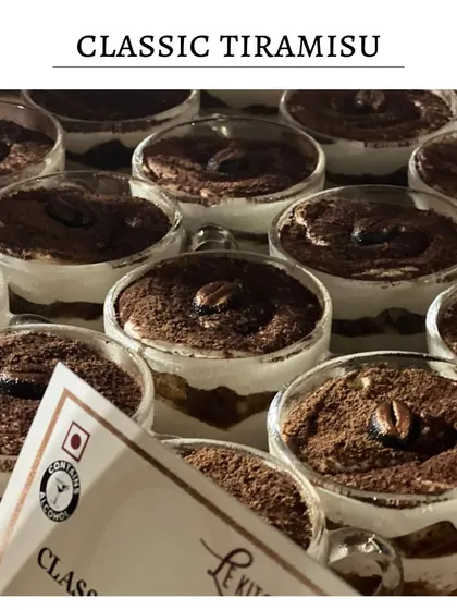 My Classic Tiramisu, served in individual glass cups. Layers of coffee-soaked ladyfingers and creamy mascarpone are dusted with cocoa powder and topped with a coffee bean.