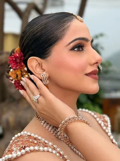A view of the complete look from the side, showing the sleek bridal bun adorned with fresh flowers. My team and I handle both hair and makeup to create a cohesive, stunning look.