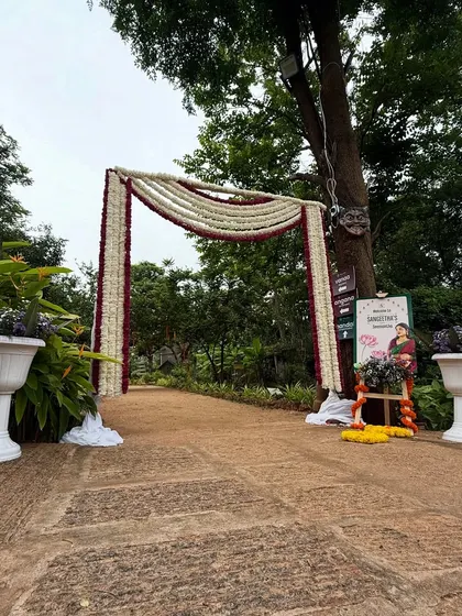 A simple yet elegant floral arch at the entrance of an outdoor baby shower venue. The white and maroon flowers create a classic and welcoming look.