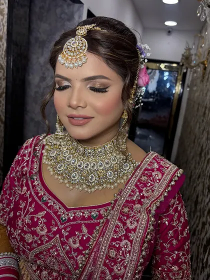 This shot showcases the elegant bridal updo, adorned with fresh flowers, which perfectly complements the makeup. It's a complete head-to-toe look designed for a modern Indian bride.