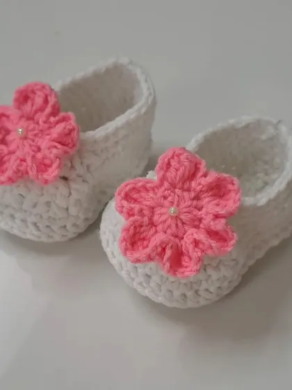 These simple white booties are brightened up with a vibrant pink flower, making them a versatile accessory for many outfits.