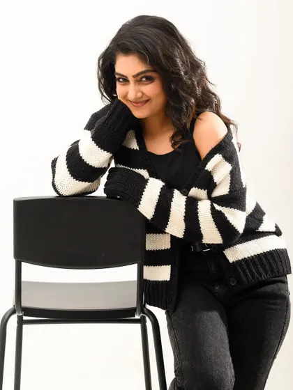 A warm and friendly portrait with a cozy striped cardigan. The simple white background and relaxed pose make this image feel very approachable and genuine.
