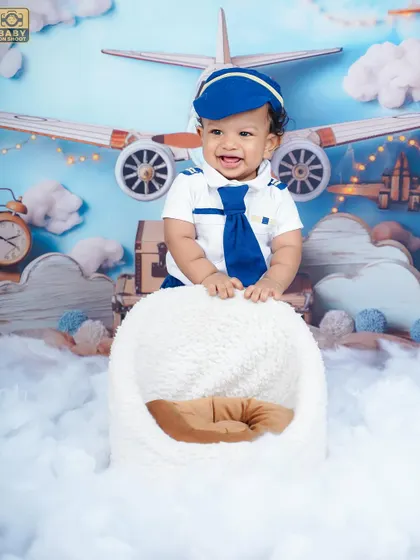 Ready for takeoff. This little pilot is all smiles in our aviator-themed setup, complete with clouds and vintage airplanes.