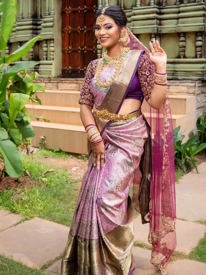 A full-length view of a model in a lavender and pink silk saree, waving gracefully. This shows the outfit's elegance in motion.