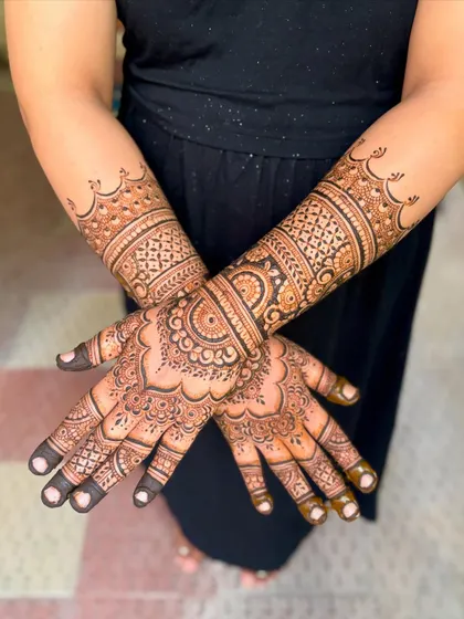 Full arm view of Kavitha's baby shower mehendi, showing the dense, celebratory patterns extending to the elbow.