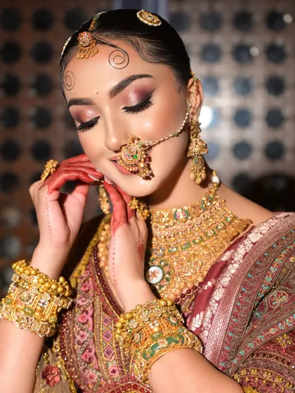 A close-up of the bride's demure pose, highlighting the beautiful pink and gold eyeshadow and the traditional henna on her hands.
