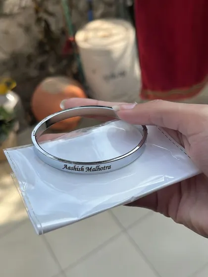 A freshly engraved silver Kada with the name 'Aashish Malhotra', shown in its protective packaging before being sent out.