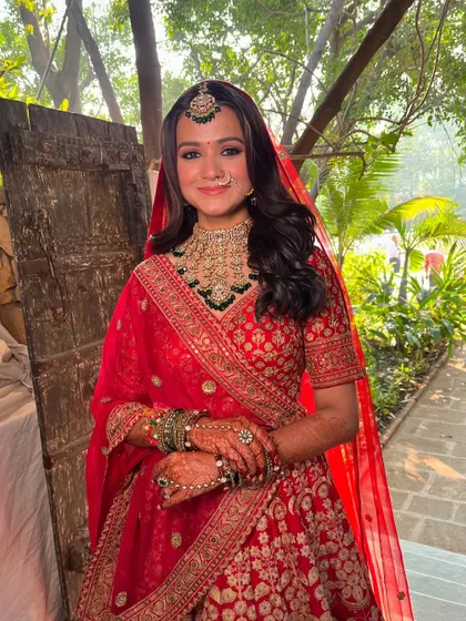 The complete bridal look, with the red veil adding a traditional touch. The makeup is radiant and long-lasting, perfect for a day full of ceremonies.