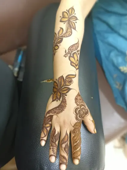 A Dubai-style design that covers the full arm, mixing bold floral outlines with delicate, paisley-shaped fillers.