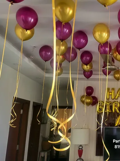 Purple and gold helium balloons with a "Happy Birthday" foil banner for a home celebration.