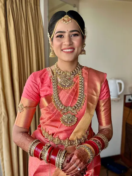 A frontal view of this stunning South Indian bridal look. The makeup is clean and minimal, letting the intricate jewelry and beautiful saree shine.