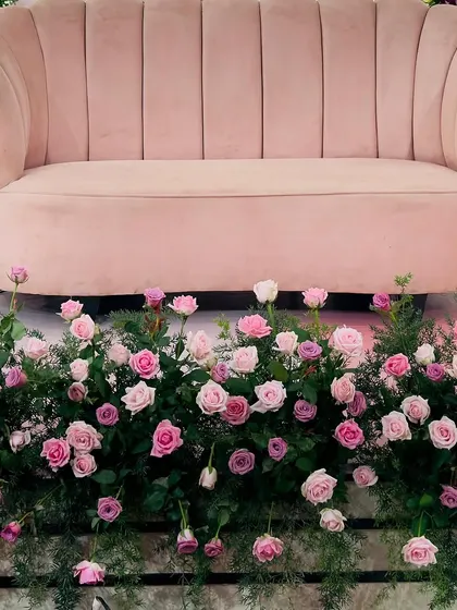 A close-up of the floral work at the base of a stage. I use a variety of fresh roses in shades of pink, nestled in lush greenery, to add a touch of natural beauty and elegance to the main seating area.
