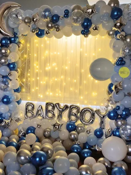 A classic "Baby Boy" welcome home setup. The silver and blue balloon frame, complete with a crescent moon and fairy lights, creates a magical and celebratory photo corner in the house.