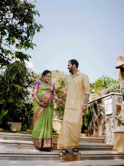 A beautiful couple's portrait during their outdoor maternity session. Dressed in traditional attire, they walk hand-in-hand, celebrating their journey to parenthood amidst a lush garden setting.