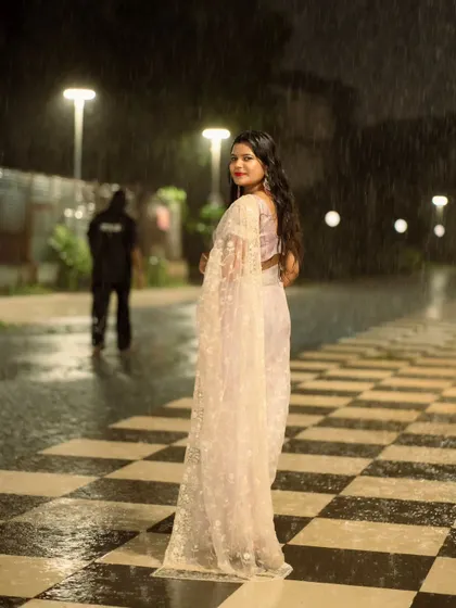 An over-the-shoulder glance from the same rainy night shoot. The glistening wet ground and soft lights create a magical atmosphere.