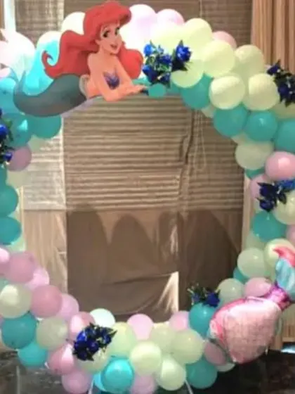 A Little Mermaid theme featuring a circular balloon arch in pastel colors and an Ariel cutout.