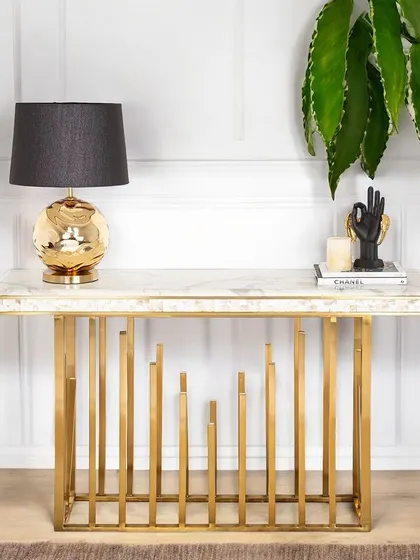 The Golden Spectra Console Table features a unique base of staggered vertical pipes, creating a sense of rhythm and modern artistry. Paired with a marble top, it's a truly stunning piece of accent furniture.