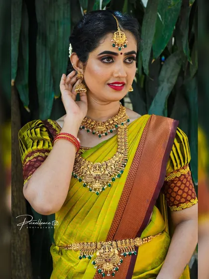 This bride's look is a perfect example of timeless elegance. The combination of her puff-sleeve blouse, temple jewellery, and classic makeup creates a truly memorable style.