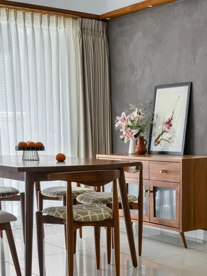 The dining area in our 'Poorna' project, where a custom crockery unit and a dark textured wall create a sophisticated and intimate setting for meals.