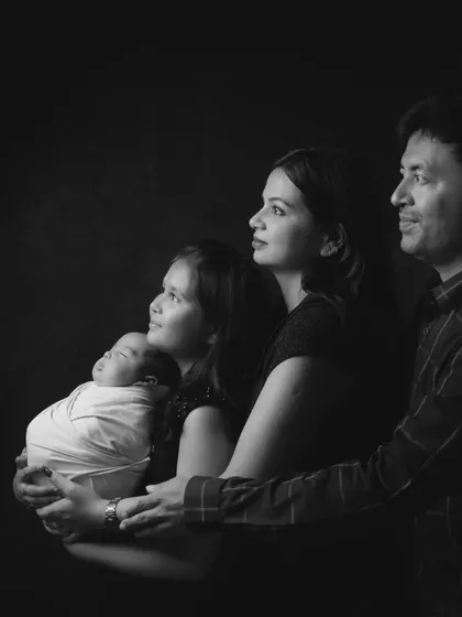 A classic black and white family portrait showing four generations, from the newborn baby to the proud father, looking towards the future.