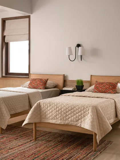 This guest bedroom is designed with twin beds, making it a versatile space for visitors. The earthy palette and simple, clean-lined furniture create a calm and restful retreat.