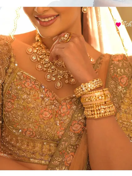 This close-up shot focuses on the bride's hands and torso, showcasing the stack of polki bangles and the intricate embroidery of her lehenga.