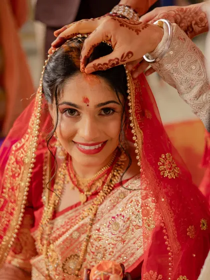 A sacred moment during the wedding ceremony. This close-up captures the groom applying the 'sindoor', with the bride's happy and emotional expression shining through her beautiful makeup.