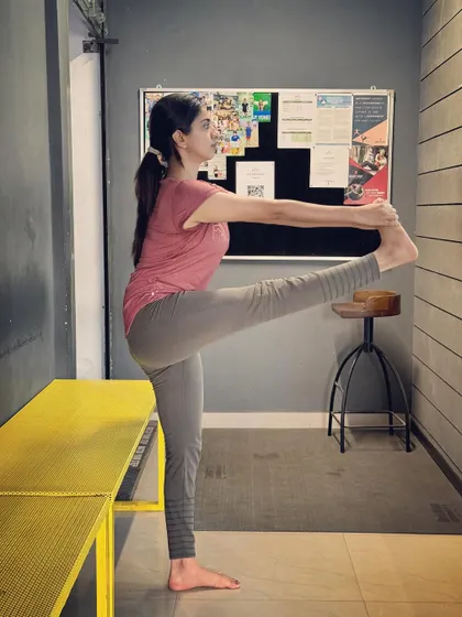 Practicing the extended hand-to-big-toe pose, a yoga asana that challenges balance while stretching the hamstrings and hips.