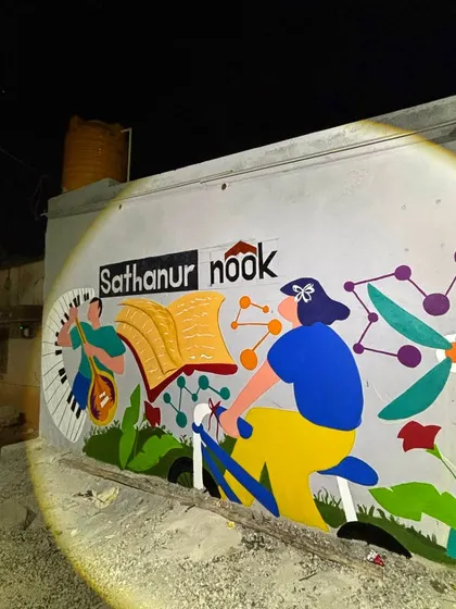 The Sathanur Nook mural glowing under a spotlight at night. It stands as a beacon of community spirit.