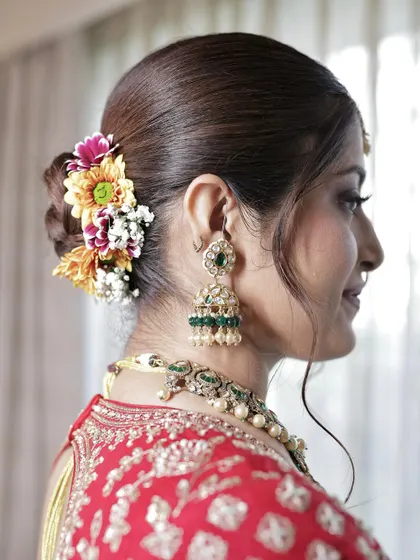 A beautiful bridal bun decorated with a mix of colorful fresh flowers, adding a vibrant touch to the traditional look.