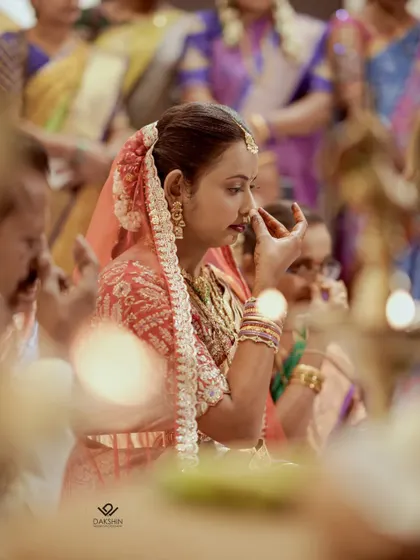 A quiet, reflective moment of a bride during her Hindu wedding ceremony, framed by the warm glow of ceremonial lamps.