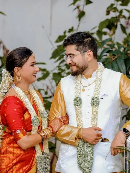 A candid portrait of a newly married couple sharing a happy moment together, adorned with traditional jasmine garlands.