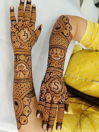 A personalized design with the couple's initials, 'S', featured prominently on the hands. The surrounding patterns are a mix of floral and geometric styles.