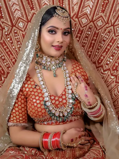 A classic pose with the bride's hand gently resting on her chest. This highlights her intricate henna design and the stunning layers of her bridal necklaces.