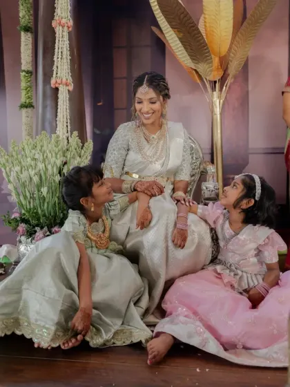 A heartwarming moment between the bride and two flower girls, with the bride's stained mehndi visible.