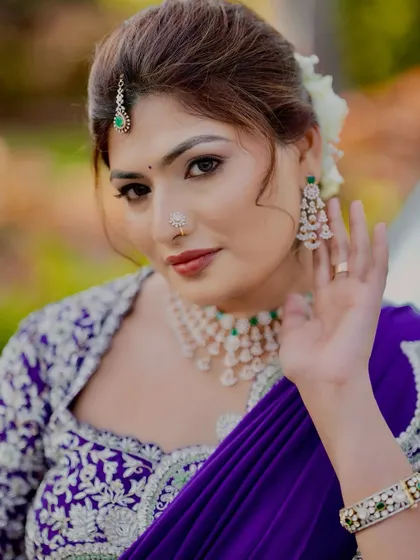 A stunning look featuring a bold purple saree and diamond jewellery. The makeup is glamorous with a defined eye and a beautiful lip color, perfect for a reception or cocktail party.