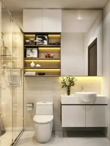 A compact bathroom design that maximizes space with a floating sink, a large mirror, and a glass shower partition. The built-in shelves with lighting add both storage and ambiance.