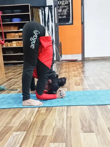 A student practices an intense forward bend, demonstrating the flexibility gained through our training program.