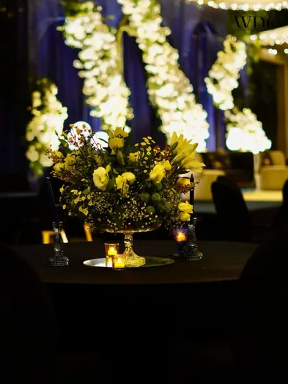 A beautiful centerpiece of white daisies, roses, and chrysanthemums, glowing in the candlelight against the dramatic backdrop of the 'Twilight Cocktail Affair' stage.