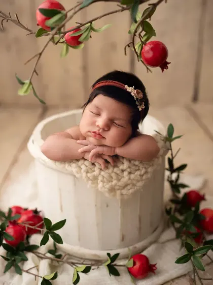 A slightly different angle of the pomegranate setup, with the branch arching over the sleeping baby, creating a beautiful natural frame.