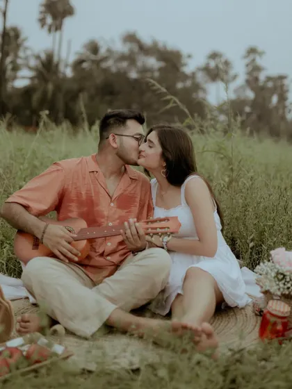 A sweet kiss shared over the guitar during their picnic pre-wedding shoot.
