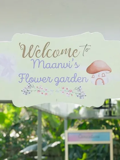 The "Welcome to Maanvi's Flower Garden" sign, framed by a rustic wooden arch and climbing ivy. This entrance piece perfectly sets the tone for a charming and natural-themed celebration.