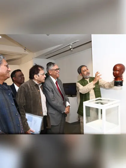 I explain a bust sculpture to visitors during my New Delhi exhibition, holding it beside the gallery display so they can look closely.