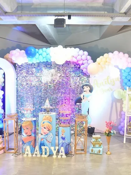 A dream come true for any princess fan. This setup includes a sparkling sequin backdrop, character cutouts of famous princesses, and custom-printed pedestals for the cake and desserts.