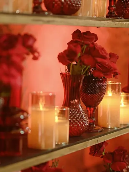 A close-up of the glowing bar back shelves, where red vases and candles create a mesmerizing display of light and color.