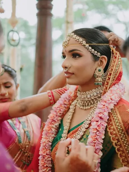 The bride getting ready with her family during her Mahuratham. This shot shows a close-up of the detailed eye makeup and the matha patti, key elements of a traditional South Indian bridal look.