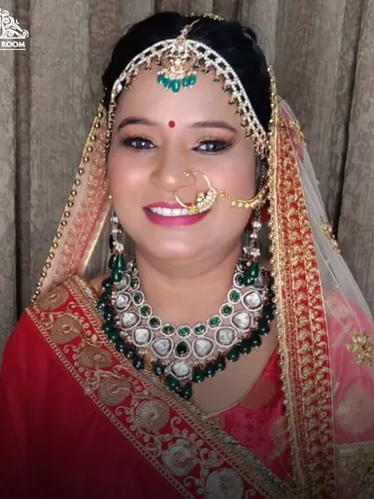 The final look of a gorgeous bride, smiling and ready for her wedding. The makeup is flawless, enhancing her natural features and complementing her green and red jewellery.