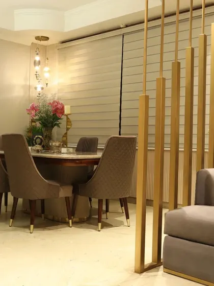A closer view of the dining area, showing the plush, quilted dining chairs and a statement hanging light fixture that adds a touch of drama.